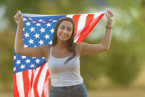 Teenage girls poses with oversize  U.S.A. flag draped over shoulders