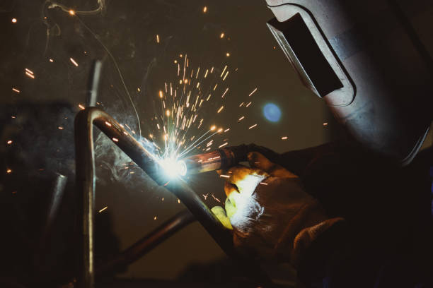 istock Industrial workshop man welding round pipe, colorful hot sparks 641381856