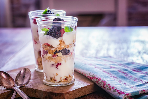 Eating healthy yogurt with cereals and fresh berries like raspberries, blueberries and blackberries