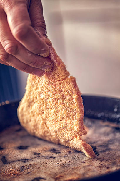 Preparing Wiener Schnitzel with beaten egg and breadcrumbs.