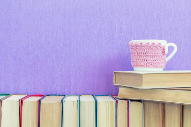 istock Many different books on violet wall and cup of tea 641390958