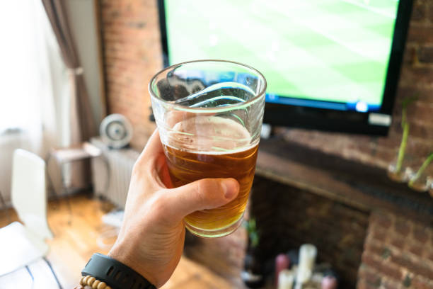 drining пива и смотреть телевизор - football human hand holding american football стоковые фото и изображения