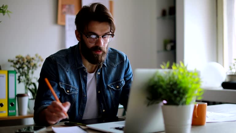 Young designer on video conference in his home office