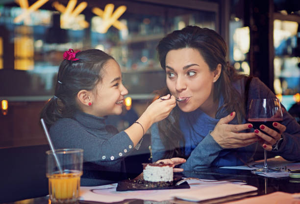 daughter is feeding her mother with cake - glasses child cute offspring imagens e fotografias de stock