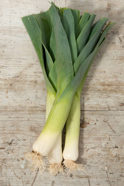 istock Leek Stalks Lying on a Wooden Surface 641406564