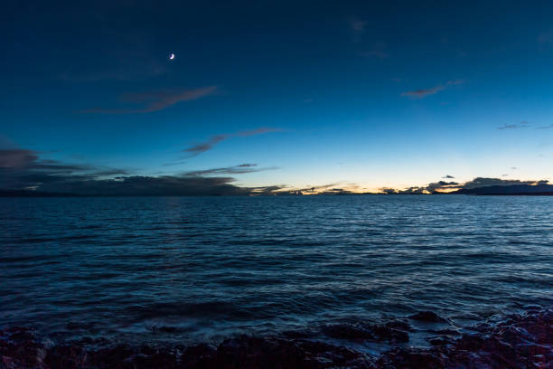 new moon hanging above calm lake