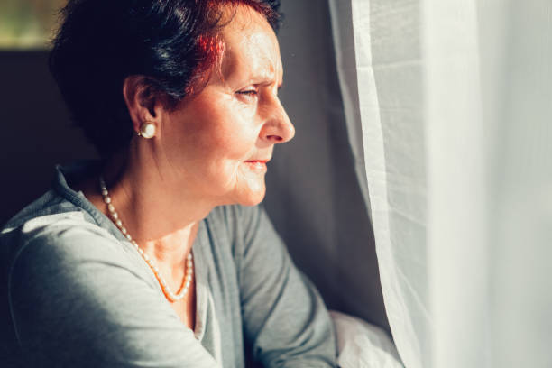 istock Senior woman looking through the window 641423136