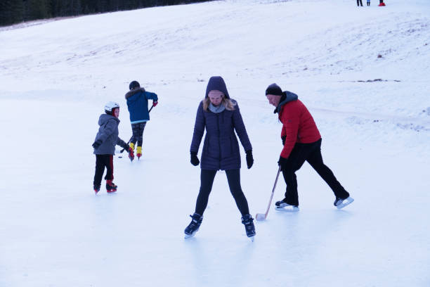 kaukaska rodzina bawi się podczas jazdy na łyżwach i gry w hokeja na lodzie na lodowisku w banff, alberta, kanada - ice skating ice hockey child family zdjęcia i obrazy z banku zdjęć