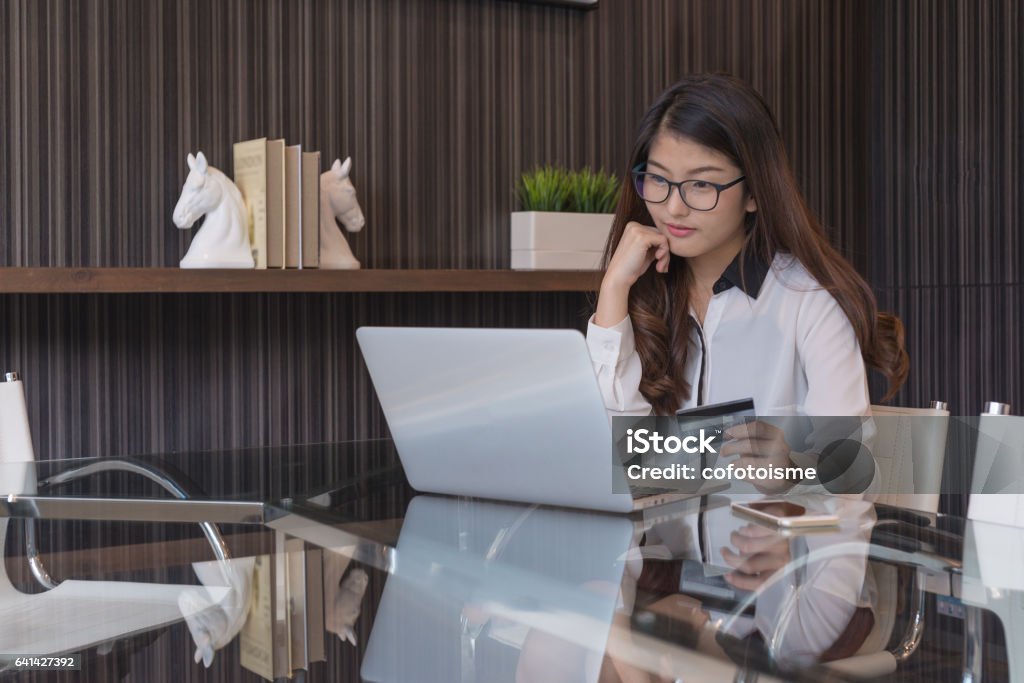 Young asia woman holding credit card and using laptop computer. Online shopping concept Adult Stock Photo