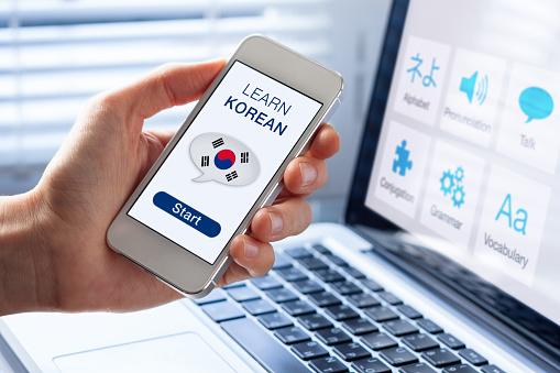 Learn Korean language online concept with a person showing e-learning app on mobile phone with the flag of South Korea