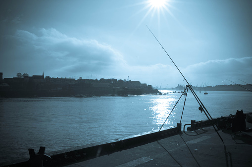 Sea fishing rod on a sunny winter's day on the quayside in the tidal part of the River Tyne at North Shields, Tyne and Wear.