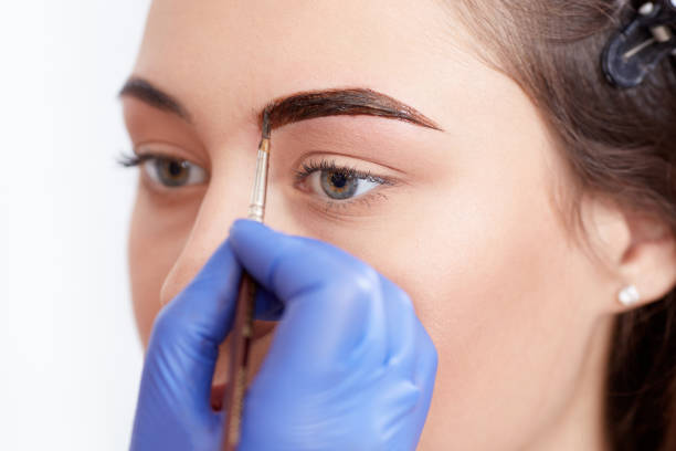 istock Cosmetologist applying special permanent make up of eyebrows 641436482