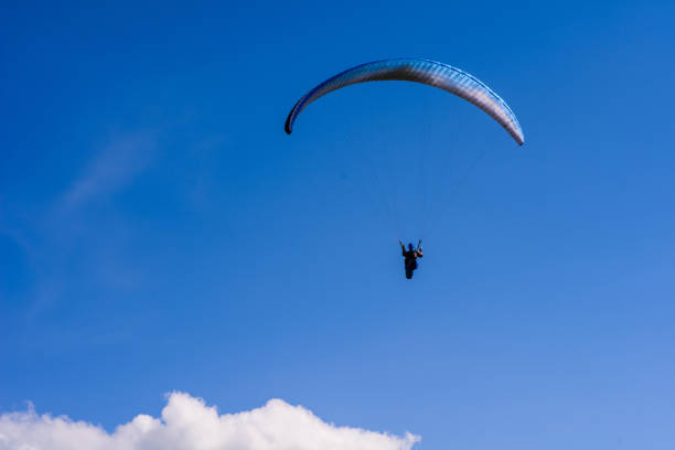 man on a parachute flying in the clear sky, a lovely summer day