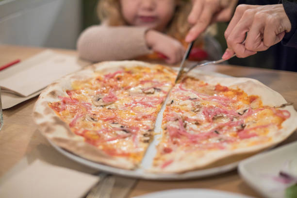 istock child looking mother hands dividing in half a pizza 641447772
