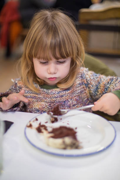 A small boy is super happy to be licking the spoon while looking at the camera