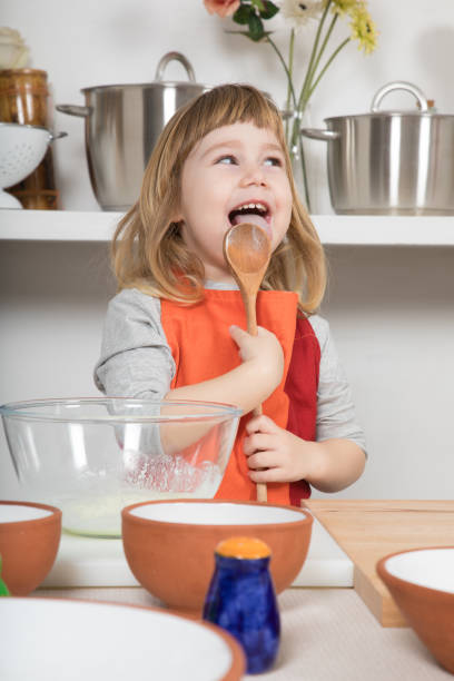 istock funny child cooking licking wooden spoon 641448440