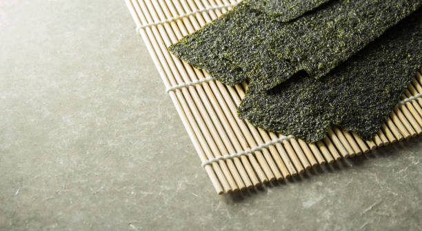 Seaweed roasted snack (nori) on mat. Seaweed roasted snack (nori) on Japanese traditional bamboo mat. nori edible seaweed sheet stock pictures, royalty-free photos & images