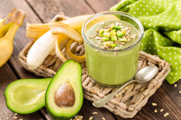Avocado and banana smoothie with oats with ingredients in glass jar on wooden background, healthy eating stock photo