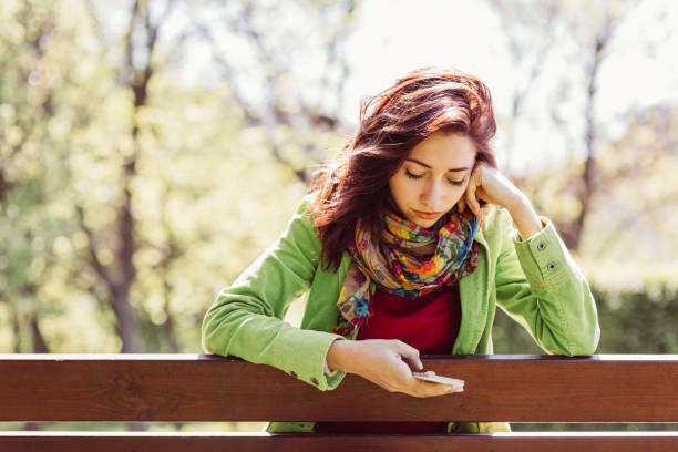 istock Young woman texting in the park 641481238