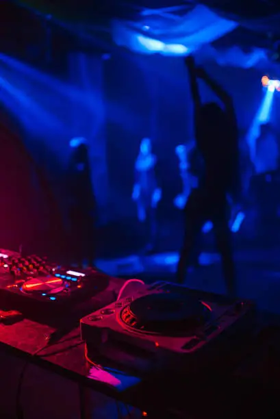 blurred silhouette of a dancing Striptease girl in a nightclub with a DJ mixer and a bar in the foreground