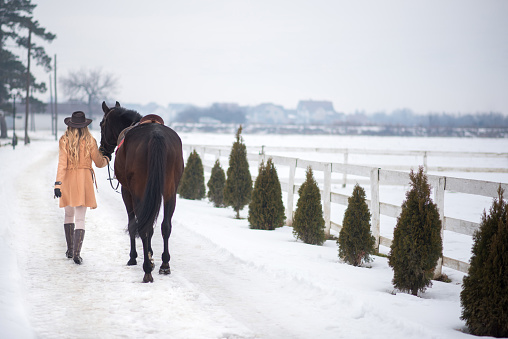 Woman jockey petting and riding her horse while enjoying winter breaks and snow