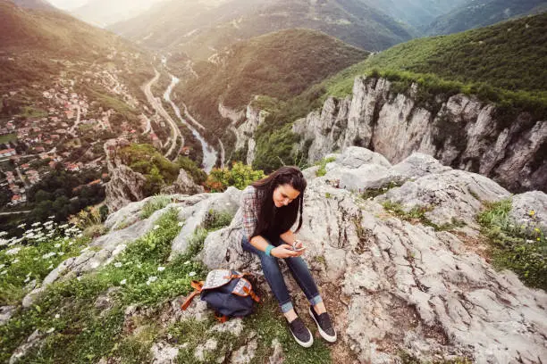 Photo of Girl texting on the mountain top
