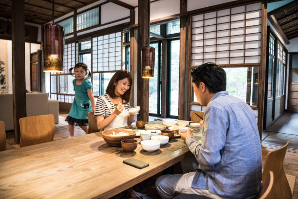 istock Japanese parents sitting at dinner table, daughter in background 641499390