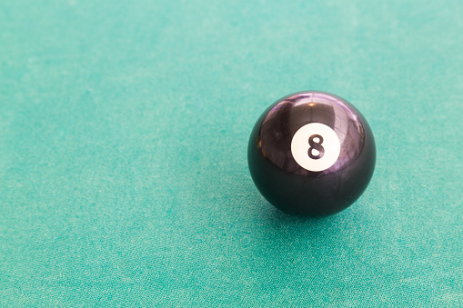 Closeup on black snooker pool billards ball on table with green surface
