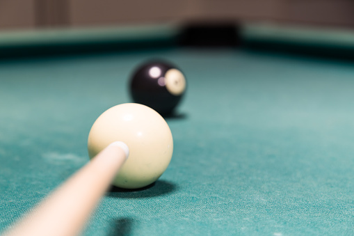 Focus on cue aiming black ball into snooker pool billards table pocket