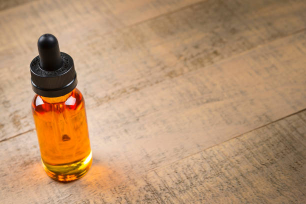 istock Vaping e-cig juice bottles over wood background. E-Juice in bottle with child proof lid. 641509464