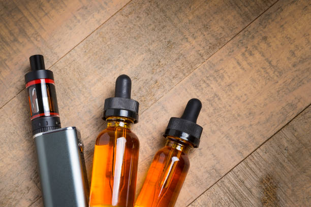 istock Vaping mod e-cig with tank atomizer and juice bottles over wood background 641509516