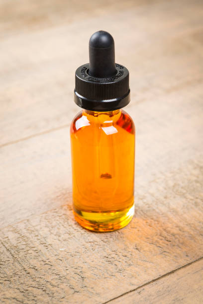 istock Vaping e-cig juice bottles over wood background. E-Juice in bottle with child proof lid. 641509576
