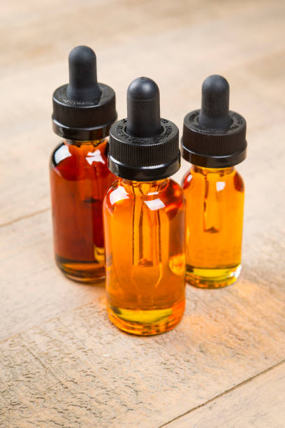 istock Vaping e-cig juice bottles over wood background. E-Juice in bottle with child proof lid. 641509580