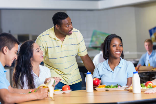 istock African American teacher talks with students at lunch 641510072