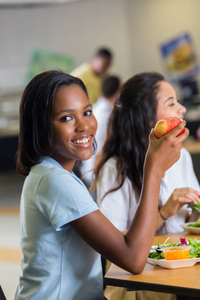 학교 식당에서 아름 다운 아프리카계 미국인 사립 고등학교 학생 - apple eating healthy eating friendship 뉴스 사진 이미지