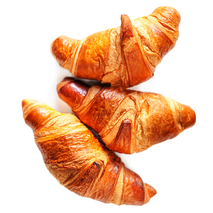 Three fresh croissants isolated isolated on white background close up