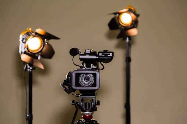 istock Video camera (camcorder) on a tripod and two halogen spotlights with Fresnel lenses 641521898