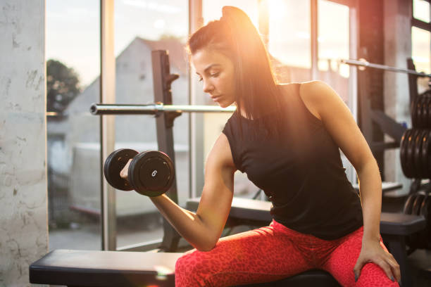 jeunes sportive soulevant des poids dans la salle de gym au coucher du soleil. - weight bench flash photos et images de collection