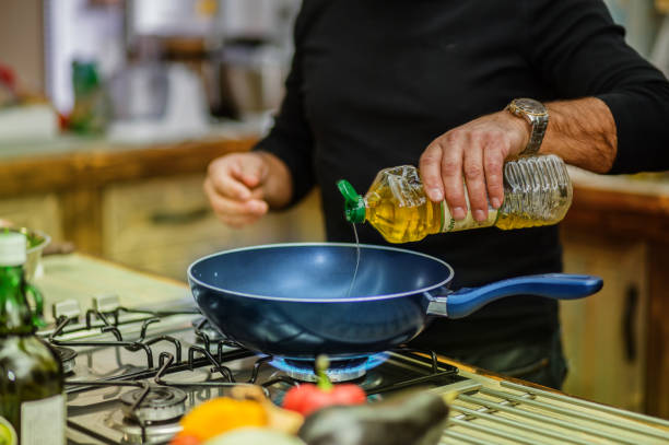 istock Chef in restaurant kitchen at stove with pan adding oil 641529652