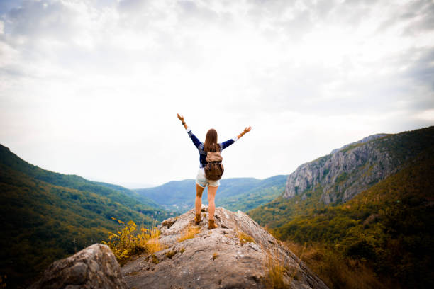 Hipster girl in sweater and shorts, hiking and having fun in the mountains on a sunny day.