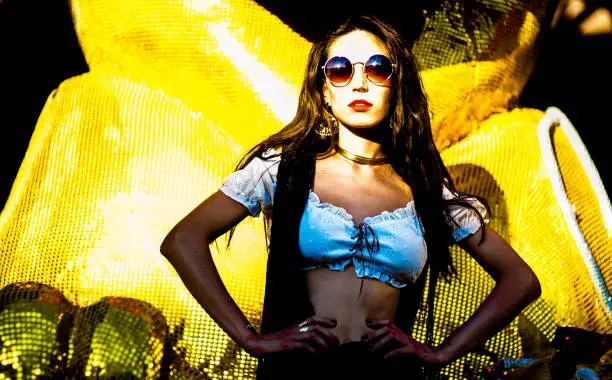 Young woman, brunette and thin, long hair, wearing sunglasses, poses outdoors