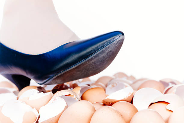 Walking on eggshells metaphor Walking on eggshells metaphor showing close-up of female human foot and ankle above broken eggshells. animal egg walking on eggshells walking broken stock pictures, royalty-free photos & images