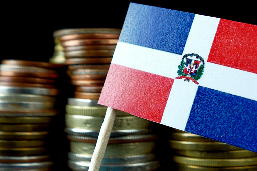Dominican Republic flag waving with stack of money coins macro