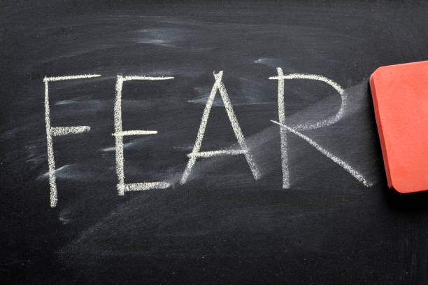 istock erasing fear, hand written word on blackboard being erased concept 641572628