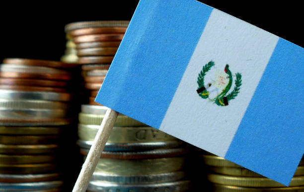 istock Guatemalan flag waving with stack of money coins macro 641574342