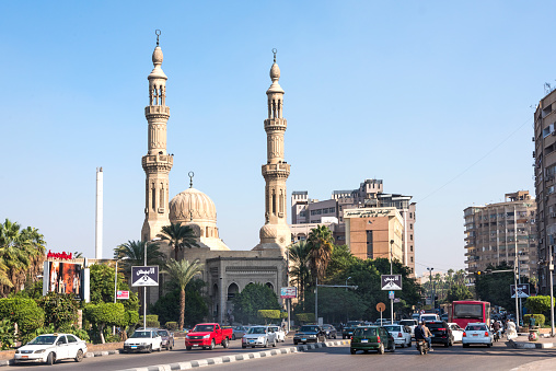 Busy street in Cairo, cars bus. On the background mosque with two minarets.