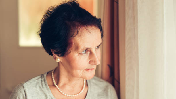 istock Senior woman at home looking through the window 641580336