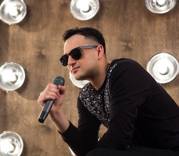 istock Male pop singer sings on scene in projectors lights 641581484