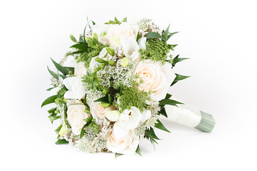 Beautiful, colorful and fresh flowers for a woman on her wedding day. Closeup of a bride holding a bouquet of roses against her white dress while getting ready for her special marriage celebration