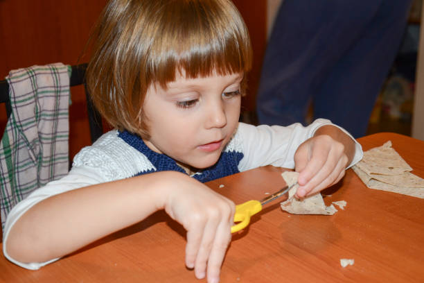 istock Happy little girl using scissors at home 641591330